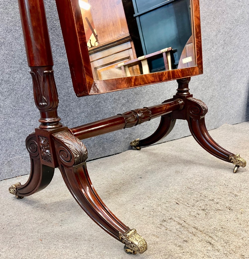 A Regency mahogany cheval mirror with a rectangular tilting frame, turned supports, and splayed legs on brass castors. View VII