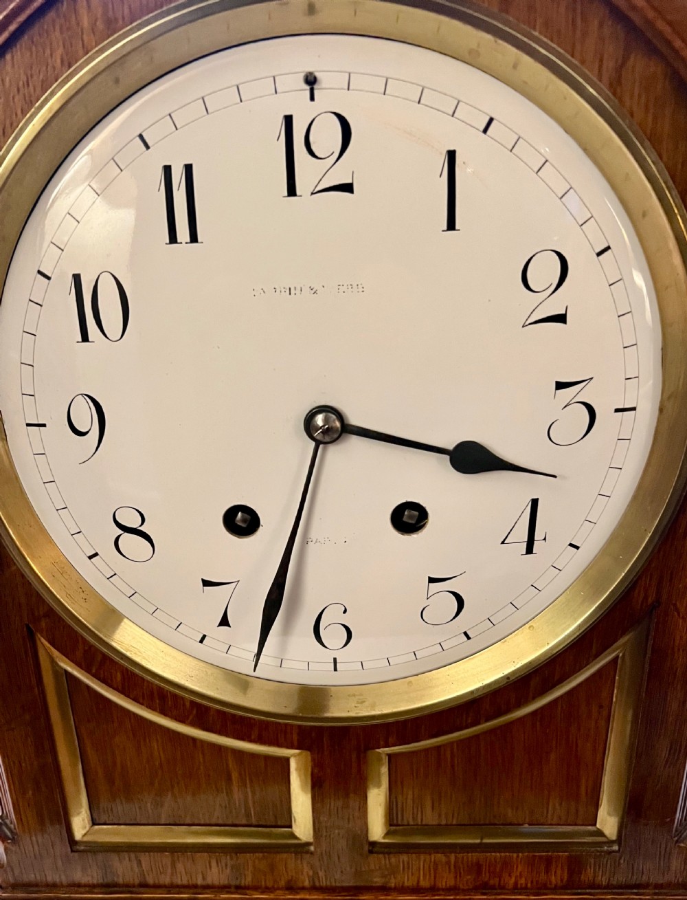 A Georgian style wooden bracket clock featuring an arched case, brass carrying handle, white dial with Arabic numerals, brass inlay, and bracket feet. View IV