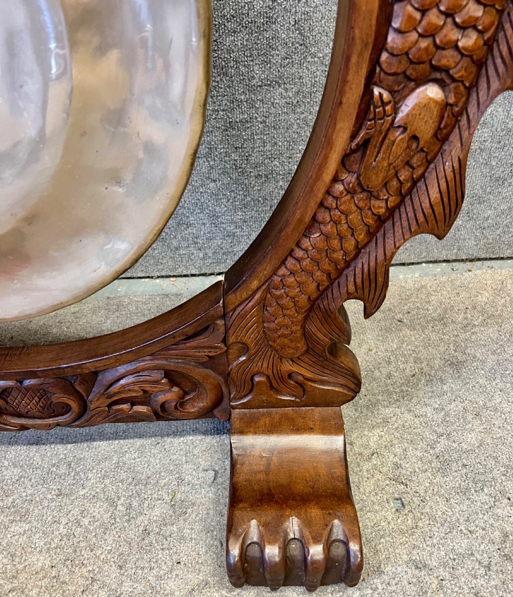 A hand-carved dark wood circular gong stand featuring twin dragon motifs and claw feet, suspending a central brass gong with a red textile mallet below. View V