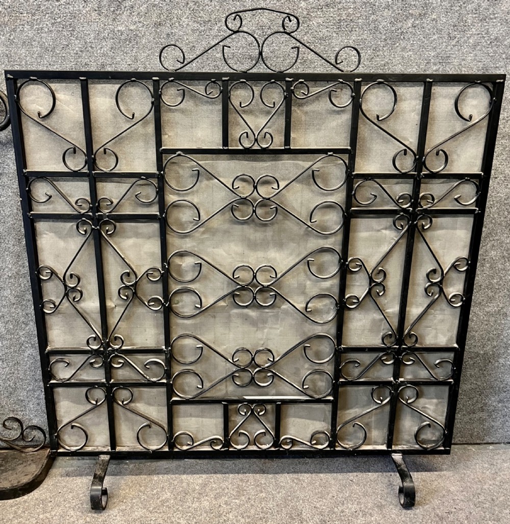 A wrought iron fire screen featuring decorative scrollwork alongside a matching companion set stand with fire tools. View II