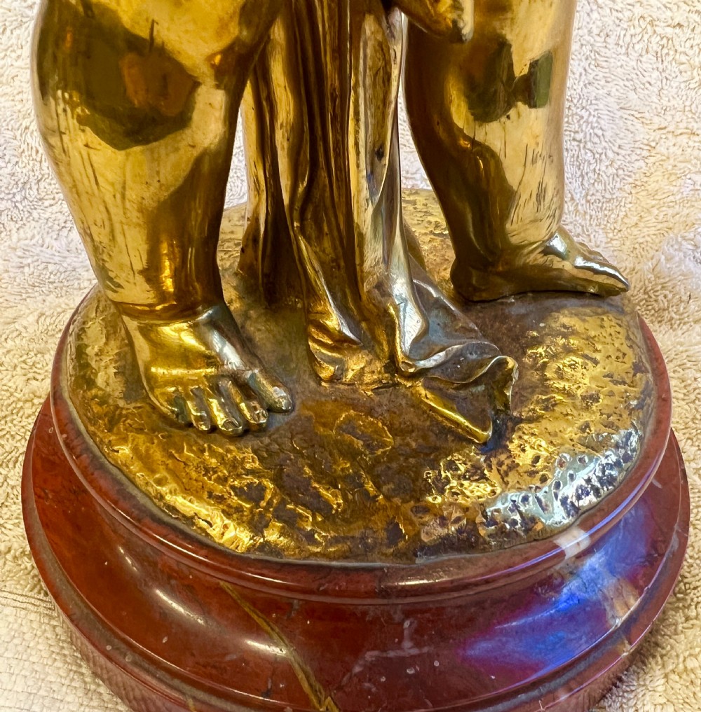 A gilt bronze sculpture depicting a young girl holding a woven basket on a circular red marble base. View VIII