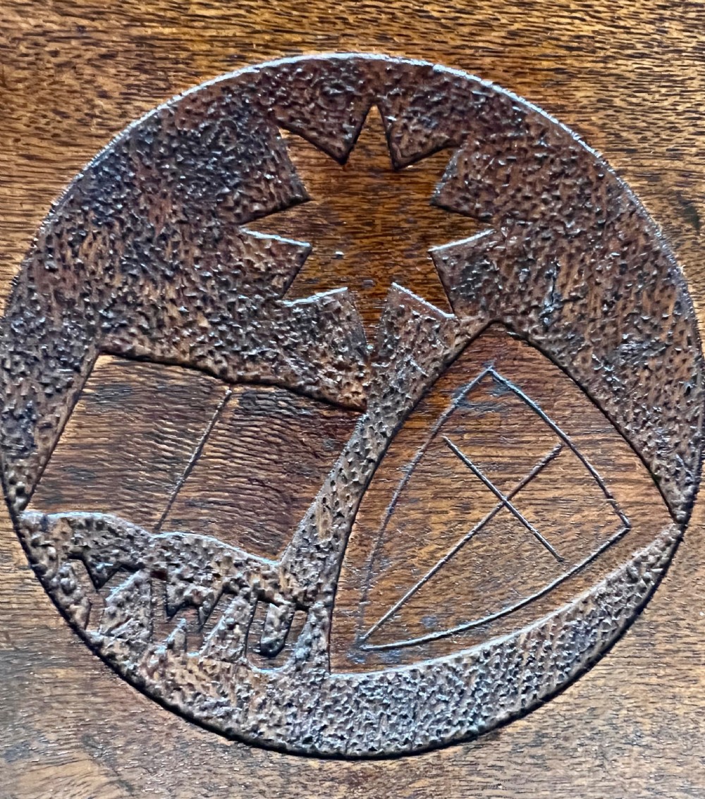 A wall-mounted carved oak letter box with a pointed top, horizontal aperture slot, side metal catch, and carved emblems on the front panel. View III