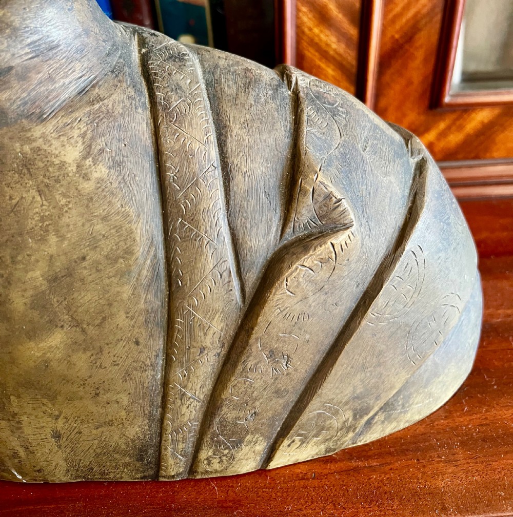 A cast bronze bust depicting a Buddha with downcast eyes, stylized hair curls, elongated earlobes, and draped robes. View IV