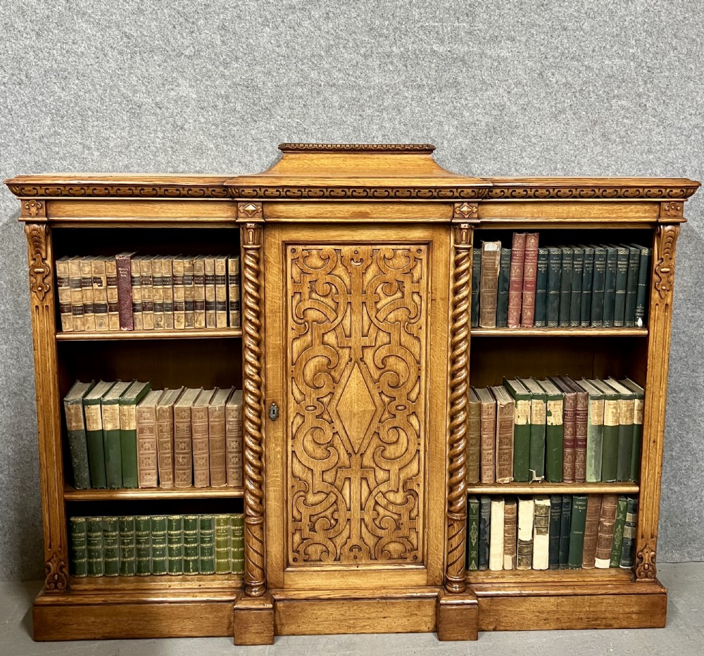 A pair of low oak open bookcases featuring raised central plinths, rope-twist columns, and intricately carved relief strapwork panels. View II