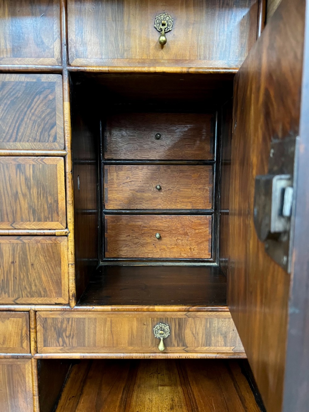 A William and Mary figured walnut escritoire featuring a double-dome arched pediment, a fall-front writing surface concealing a multi-drawer fitted interior, and a chest base on turned bun feet. View IV