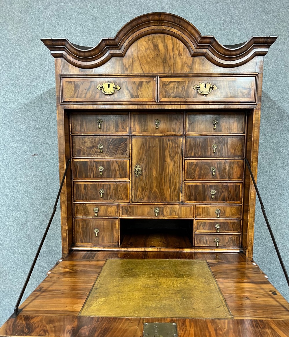 A William and Mary figured walnut escritoire featuring a double-dome arched pediment, a fall-front writing surface concealing a multi-drawer fitted interior, and a chest base on turned bun feet. View VI