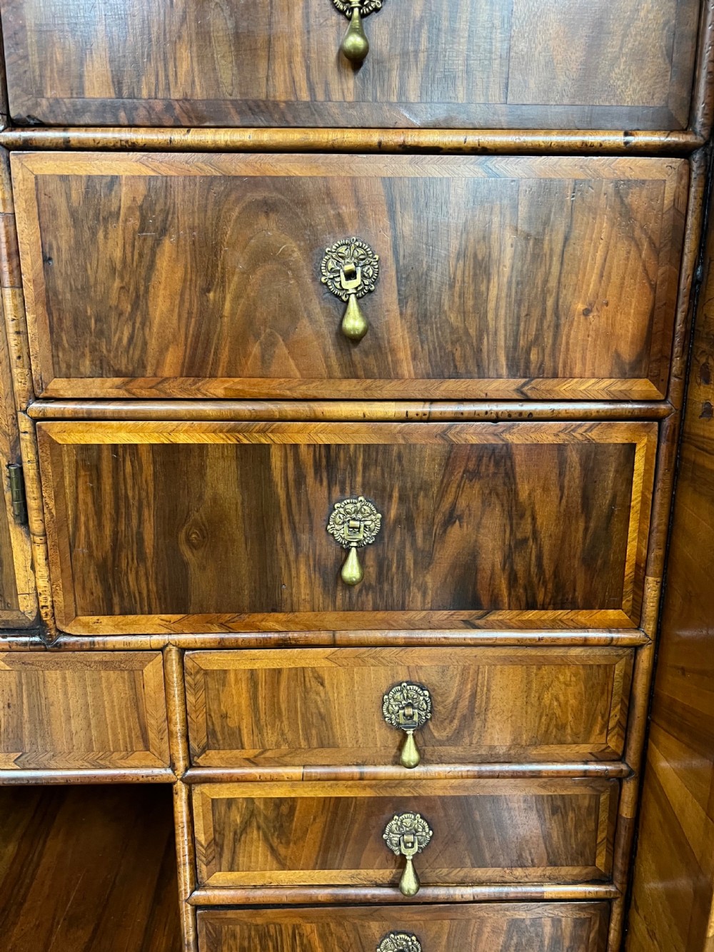 A William and Mary figured walnut escritoire featuring a double-dome arched pediment, a fall-front writing surface concealing a multi-drawer fitted interior, and a chest base on turned bun feet. View VII