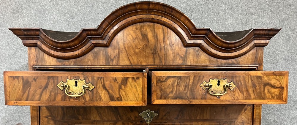 A William and Mary figured walnut escritoire featuring a double-dome arched pediment, a fall-front writing surface concealing a multi-drawer fitted interior, and a chest base on turned bun feet. View IX