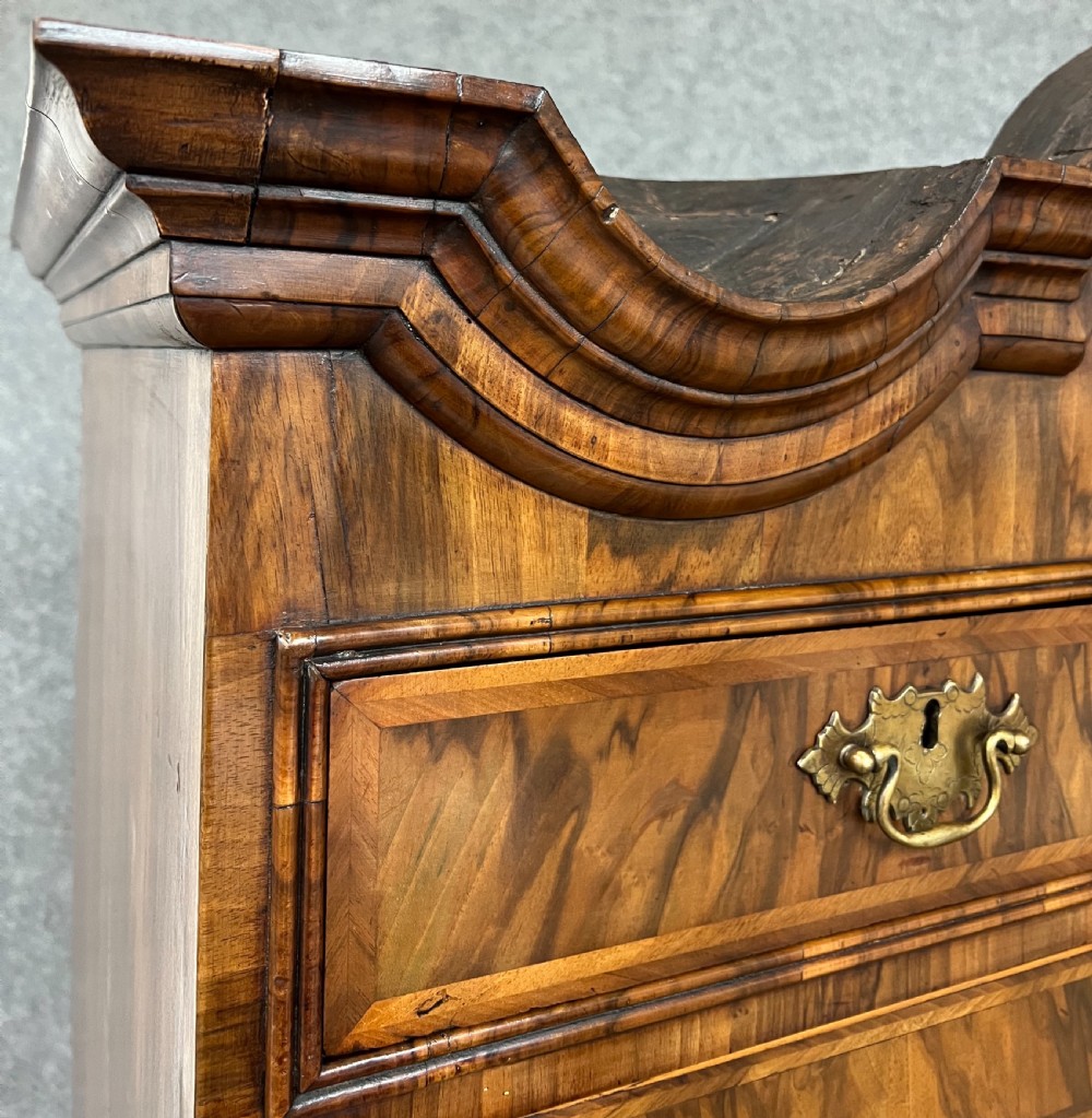 A William and Mary figured walnut escritoire featuring a double-dome arched pediment, a fall-front writing surface concealing a multi-drawer fitted interior, and a chest base on turned bun feet. View X