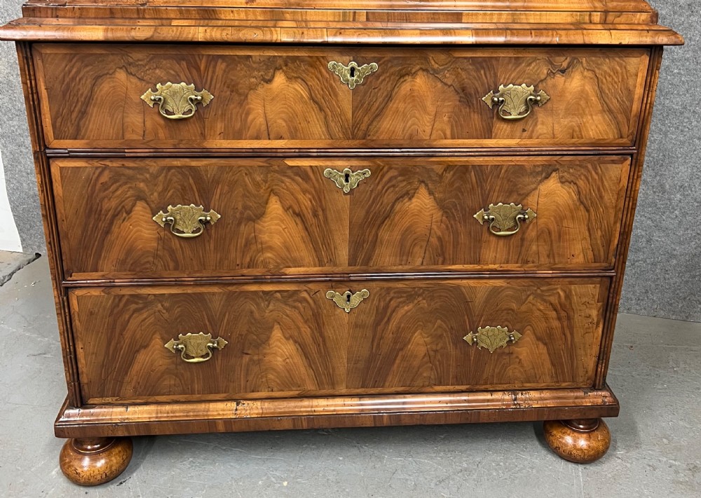A William and Mary figured walnut escritoire featuring a double-dome arched pediment, a fall-front writing surface concealing a multi-drawer fitted interior, and a chest base on turned bun feet. View XI