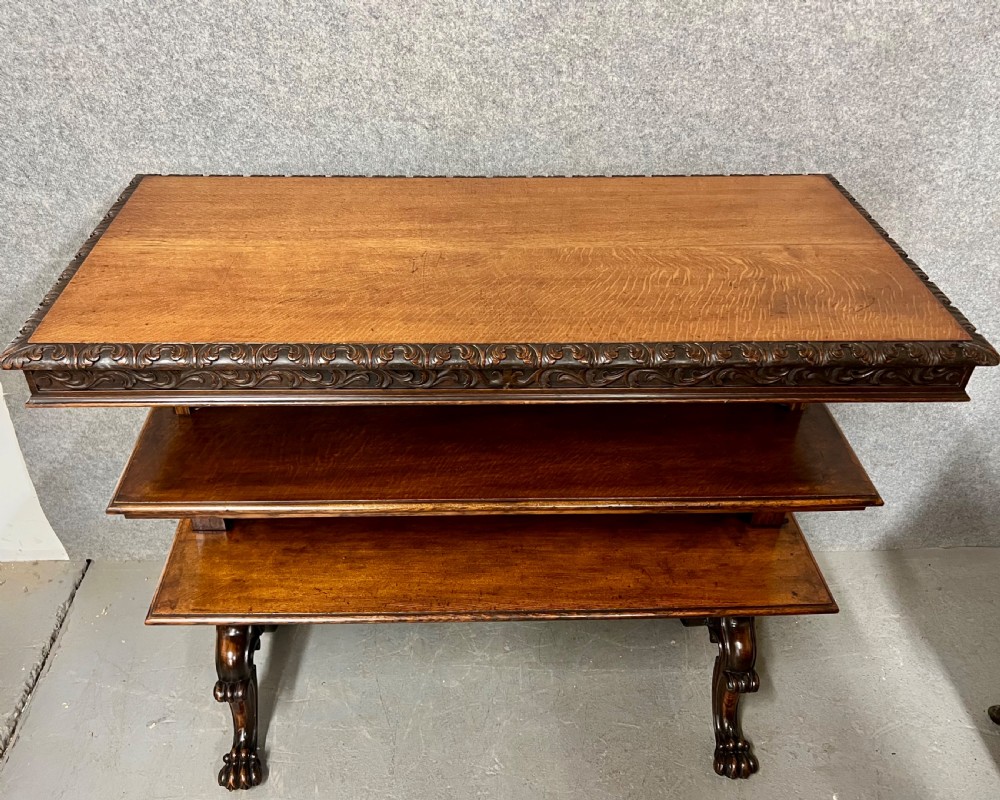 A dark oak Victorian rise and fall three-tiered dumb waiter with carved foliage borders and ornate leg supports. View X