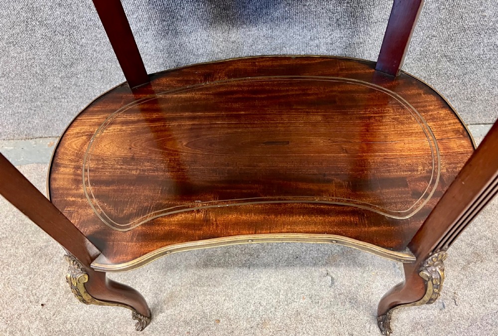 An oval French bijouterie table featuring mahogany wood framing, glass display panels lined with red fabric, gilt brass mounts, and fluted legs connected by a lower shelf. View VIII