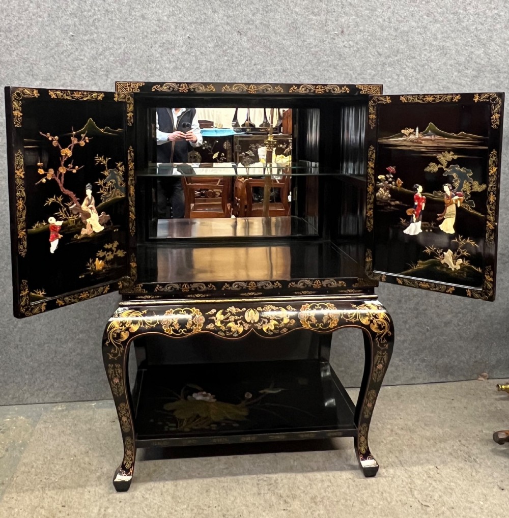 A black lacquered Chinoiserie cocktail cabinet on stand featuring hand-painted botanical motifs, birds, figures, and gilt cabriole legs. View II