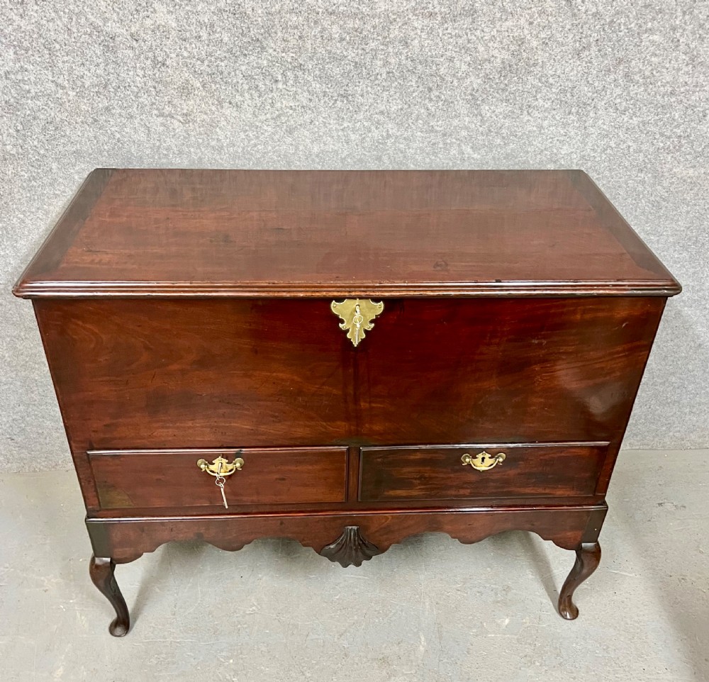 A George II mahogany chest on stand featuring a hinged top, two lower drawers with brass keyplates, a central carved shell apron, and cabriole legs. View III