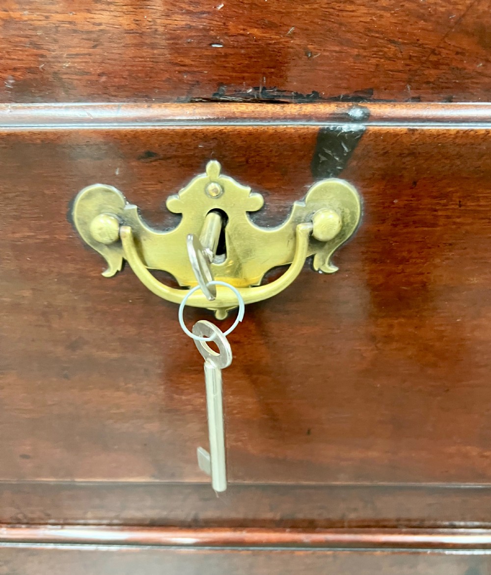 A George II mahogany chest on stand featuring a hinged top, two lower drawers with brass keyplates, a central carved shell apron, and cabriole legs. View IV