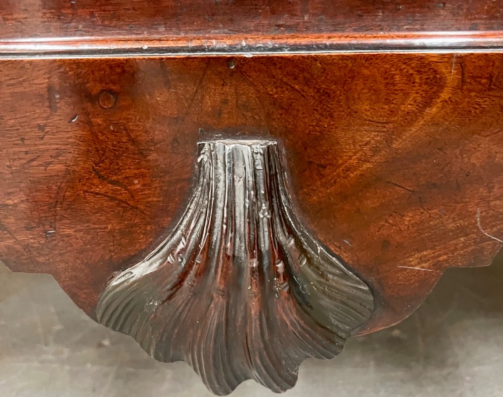 A George II mahogany chest on stand featuring a hinged top, two lower drawers with brass keyplates, a central carved shell apron, and cabriole legs. View VI