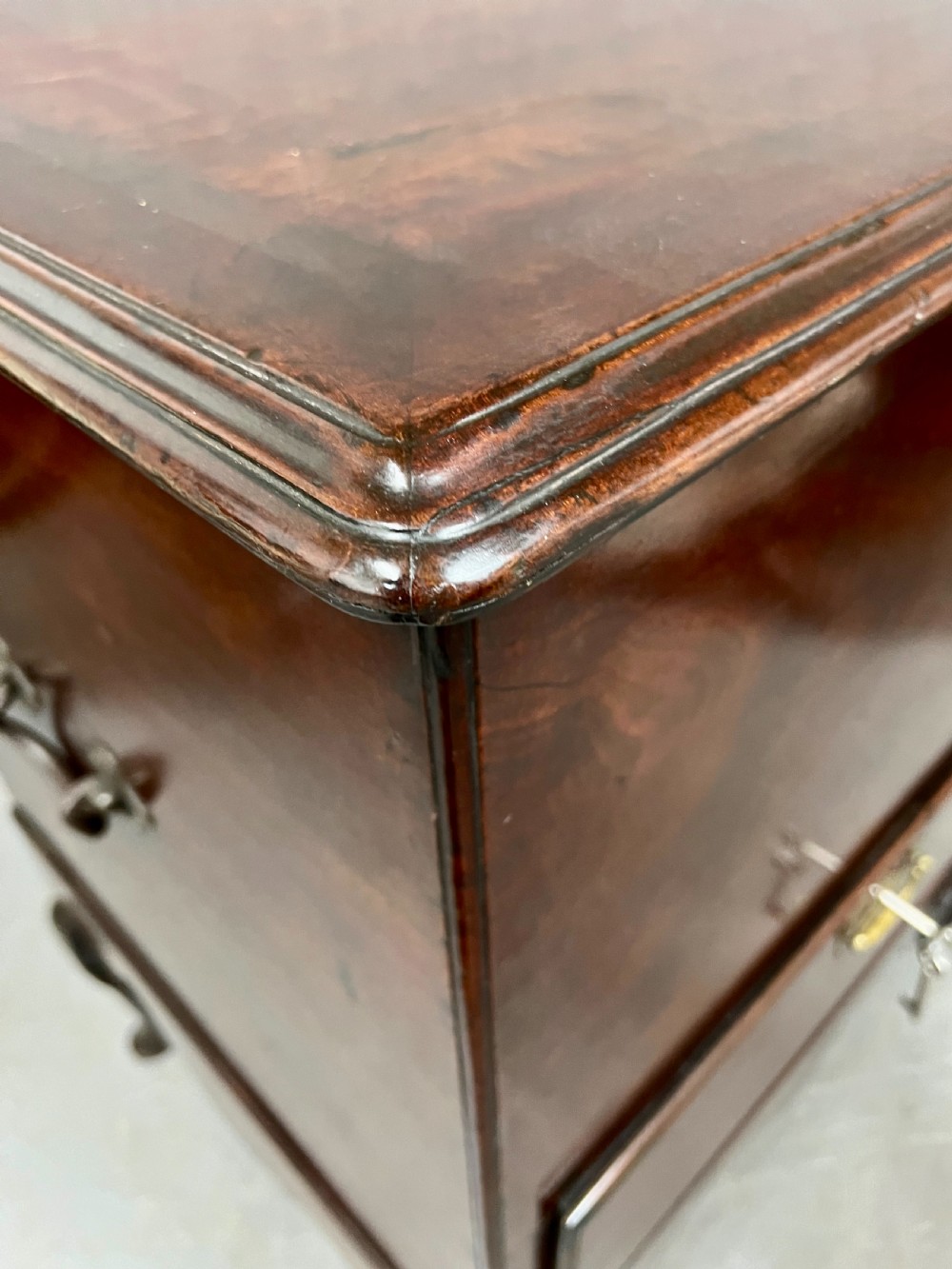 A George II mahogany chest on stand featuring a hinged top, two lower drawers with brass keyplates, a central carved shell apron, and cabriole legs. View XII