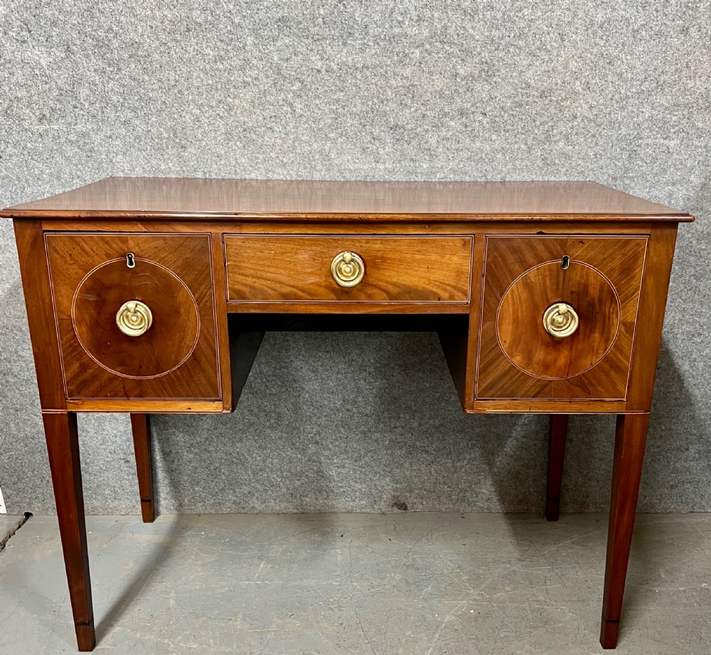 A small Georgian mahogany sideboard featuring three drawers with circular veneered panels, brass ring handles, and four square tapered legs.