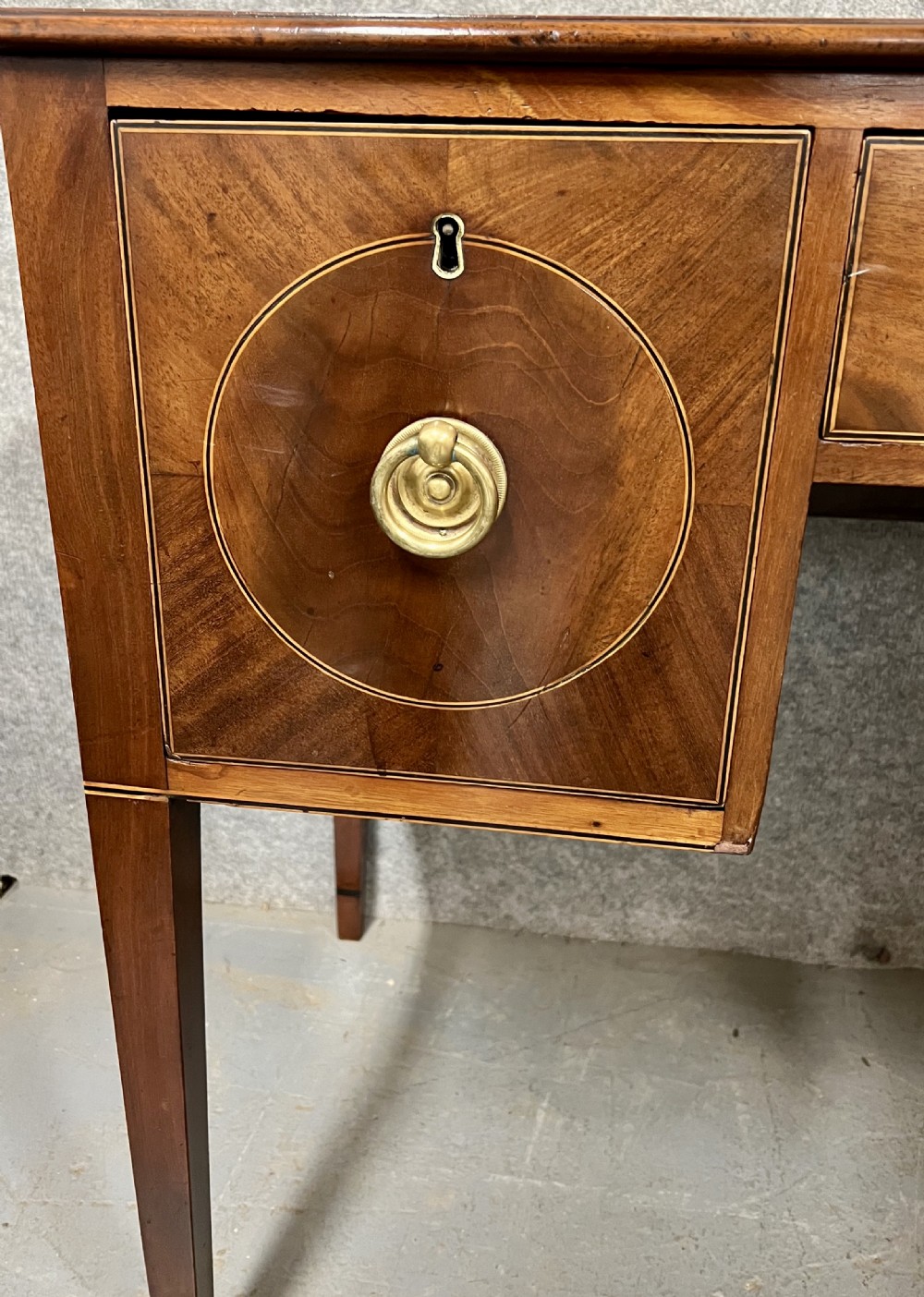 A small Georgian mahogany sideboard featuring three drawers with circular veneered panels, brass ring handles, and four square tapered legs. View II