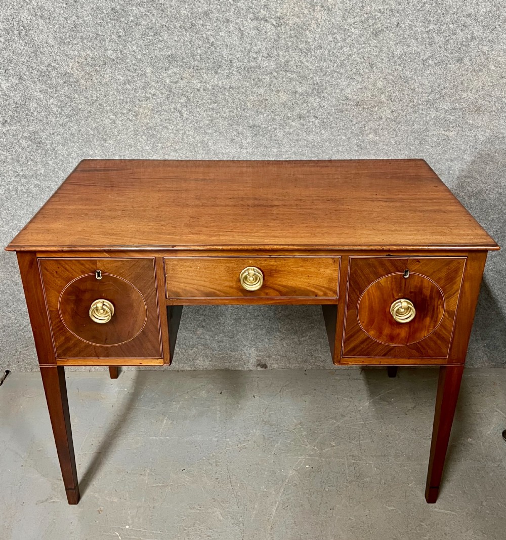 A small Georgian mahogany sideboard featuring three drawers with circular veneered panels, brass ring handles, and four square tapered legs. View III