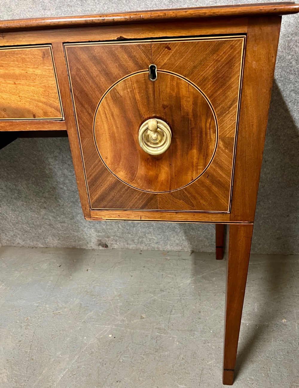 A small Georgian mahogany sideboard featuring three drawers with circular veneered panels, brass ring handles, and four square tapered legs. View IV