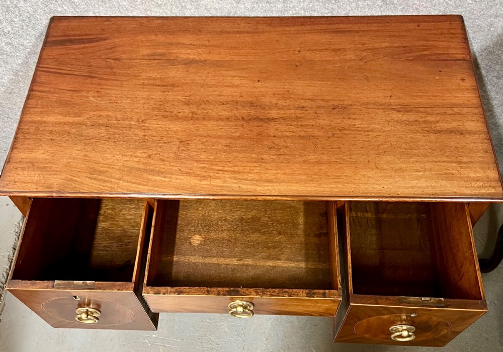 A small Georgian mahogany sideboard featuring three drawers with circular veneered panels, brass ring handles, and four square tapered legs. View VI