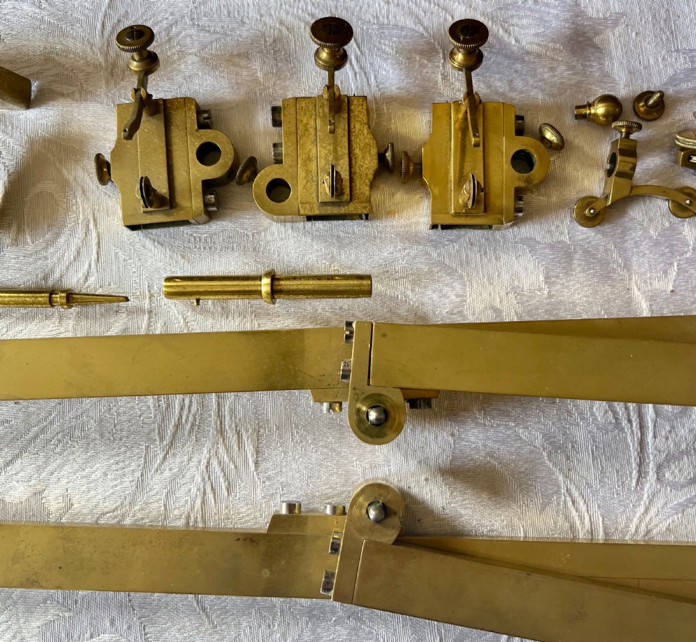 An antique brass pantograph with various small attachments laid out alongside its open fitted mahogany case with green felt lining. View IV