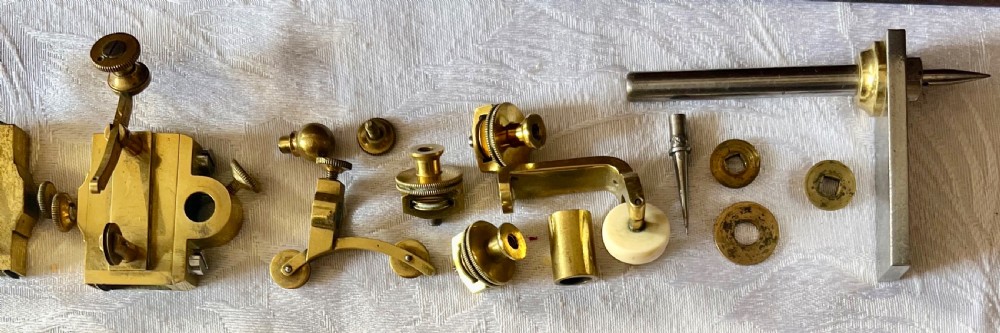 An antique brass pantograph with various small attachments laid out alongside its open fitted mahogany case with green felt lining. View V