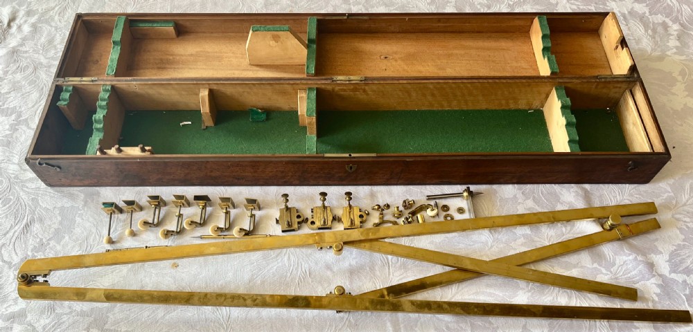 An antique brass pantograph with various small attachments laid out alongside its open fitted mahogany case with green felt lining. View VIII