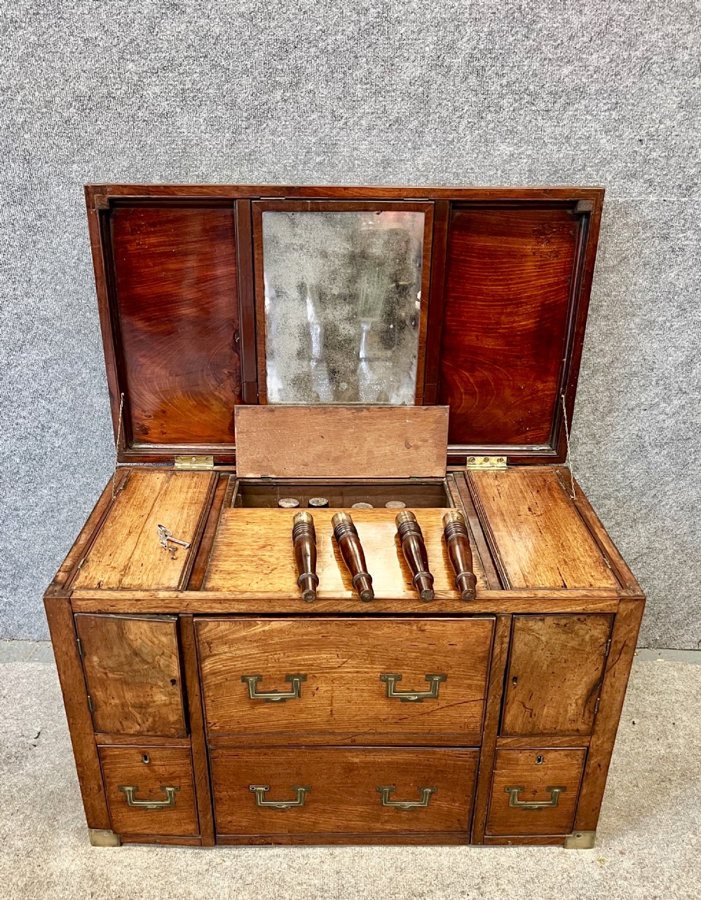 A George III mahogany campaign dressing chest featuring a hinged top revealing an adjustable mirror, brass corner mounts, flush handles, and turned legs. View IV