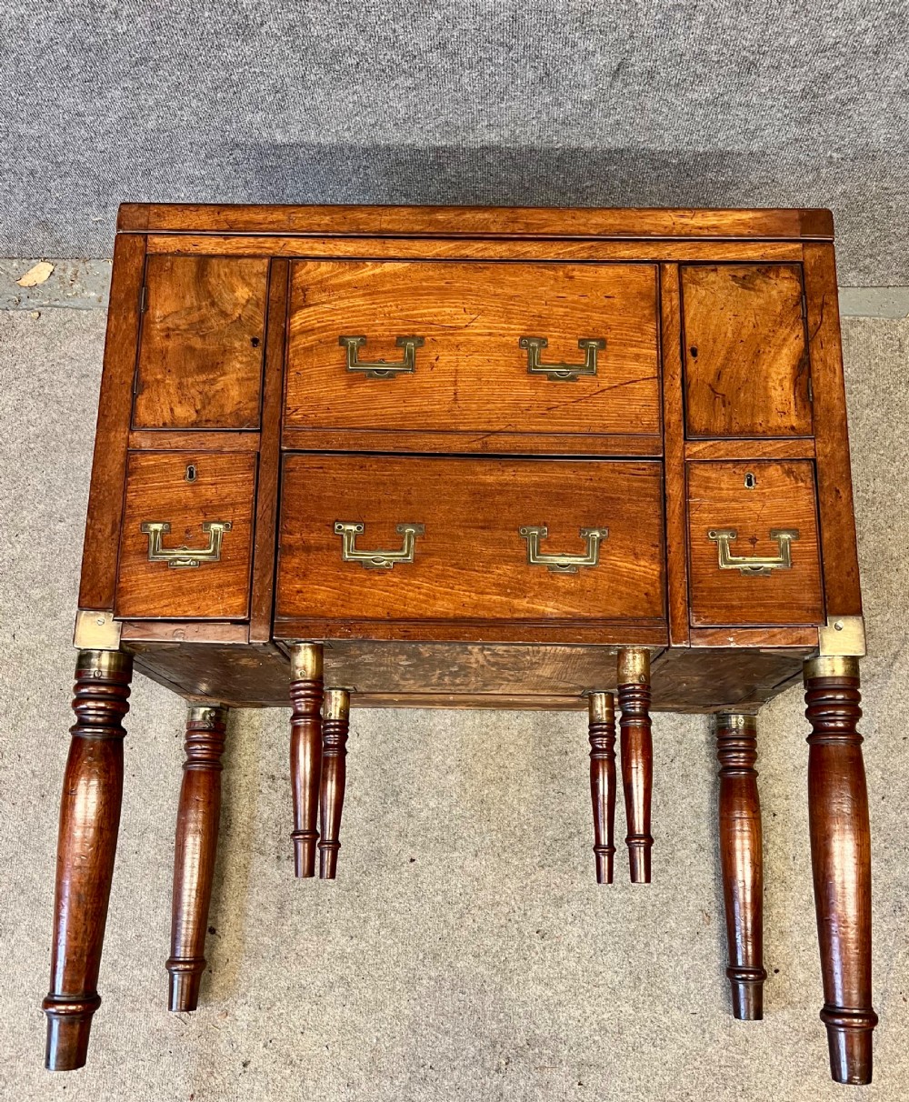 A George III mahogany campaign dressing chest featuring a hinged top revealing an adjustable mirror, brass corner mounts, flush handles, and turned legs. View VIII