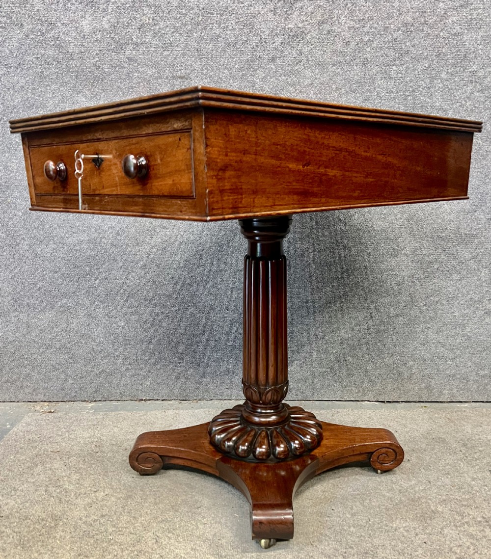 Antique William IV mahogany occasional table with two drawers, a reeded pedestal stem, and a scroll-foot base on brass castors.