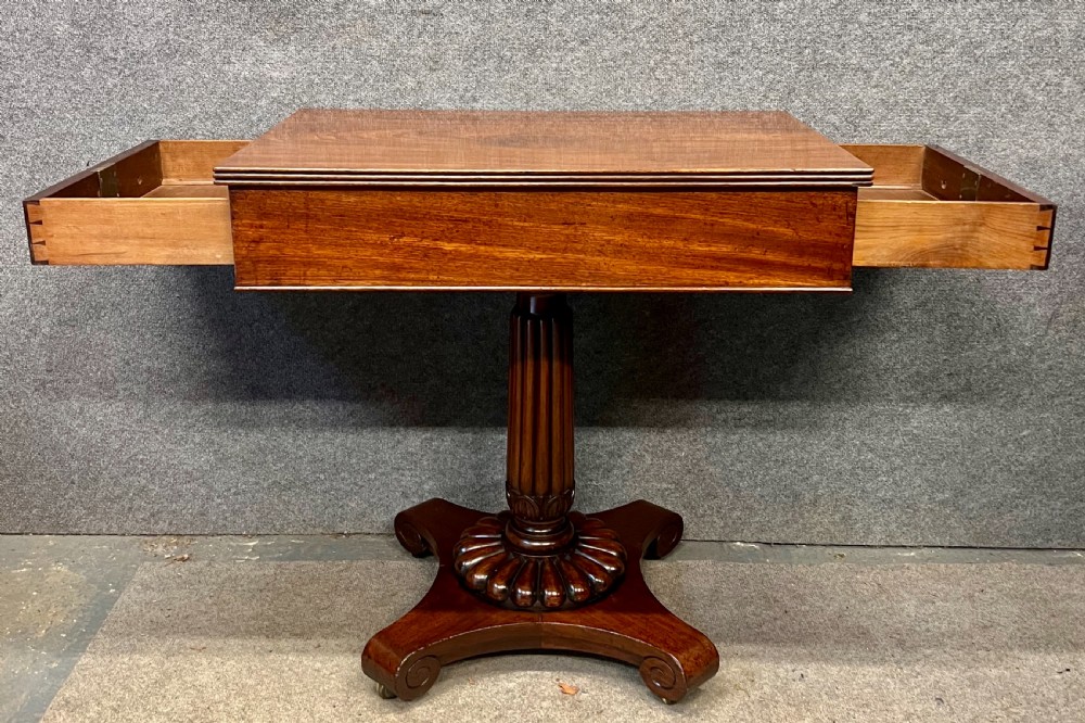 Antique William IV mahogany occasional table with two drawers, a reeded pedestal stem, and a scroll-foot base on brass castors. View III