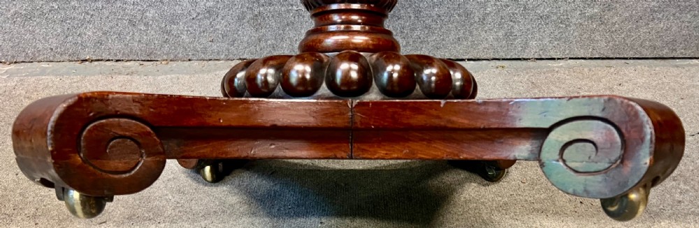Antique William IV mahogany occasional table with two drawers, a reeded pedestal stem, and a scroll-foot base on brass castors. View VIII