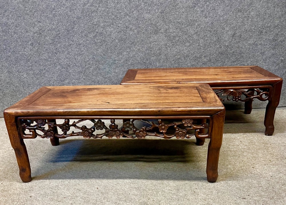A matched pair of rectangular Chinese low hardwood tables with intricately carved openwork floral aprons and curved legs.
