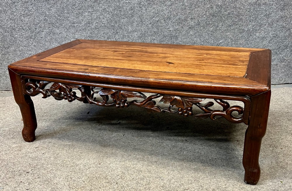 A matched pair of rectangular Chinese low hardwood tables with intricately carved openwork floral aprons and curved legs. View II
