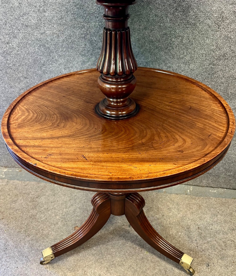 A Regency mahogany two-tier table with circular dished surfaces, a central reeded column, and a tripod base on brass castors. View IV