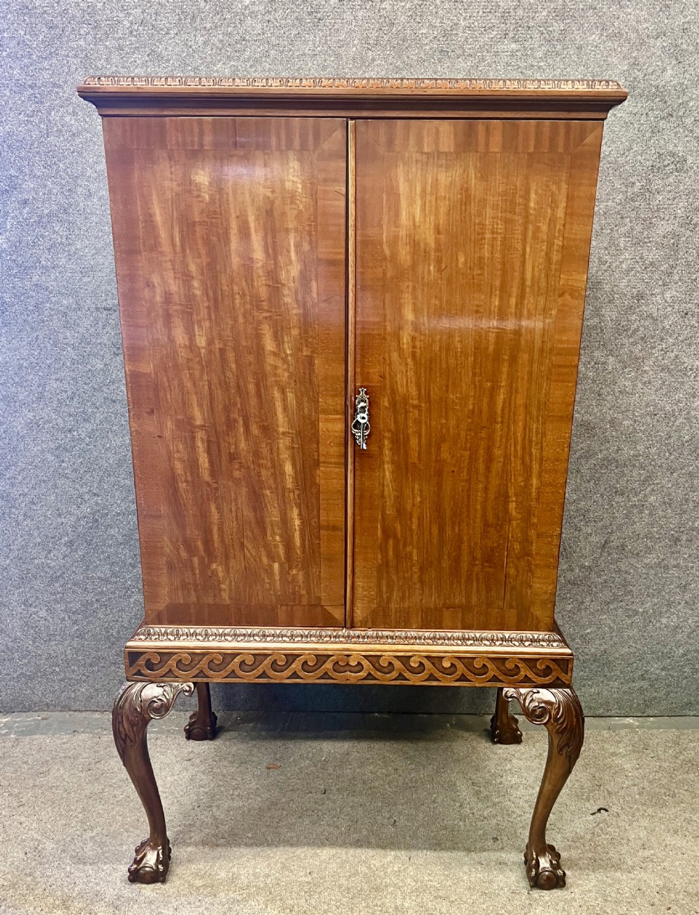 An open Edwardian mahogany folio cabinet featuring twin doors, internal sliding trays, carved top moulding, and claw and ball feet. View II