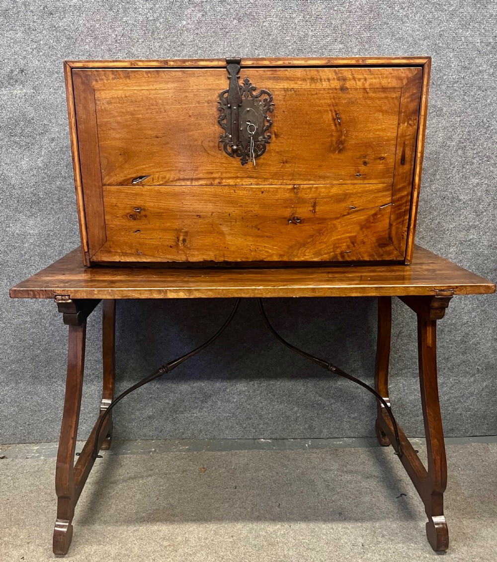 A 17th-century Spanish walnut Vargueno cabinet with an open drop-front writing flap revealing multiple fitted drawers, set on a trestle stand with iron stretchers. View II