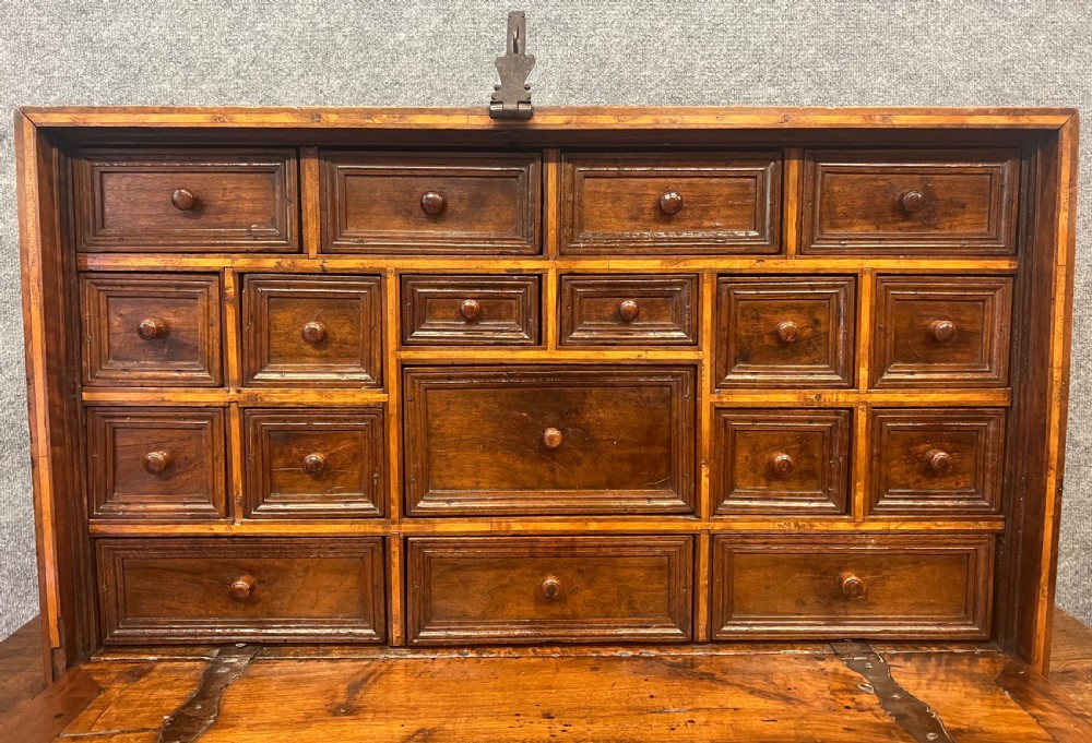 A 17th-century Spanish walnut Vargueno cabinet with an open drop-front writing flap revealing multiple fitted drawers, set on a trestle stand with iron stretchers. View IV