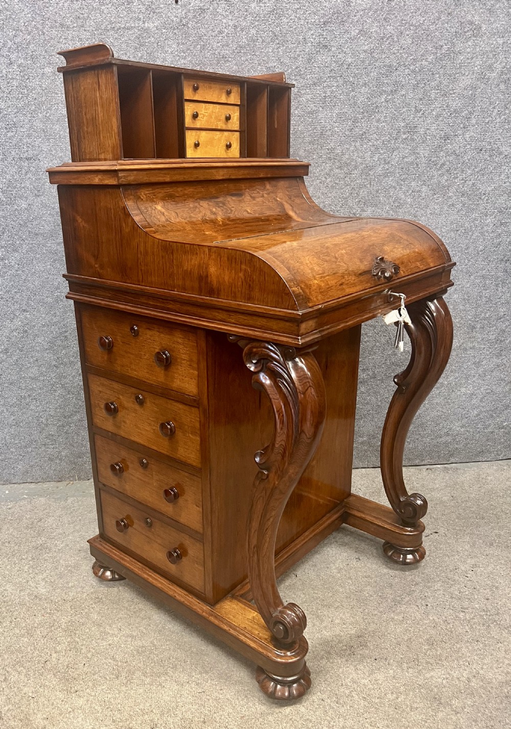 A Victorian rosewood davenport desk with an elevated pop-up stationery gallery, slanted piano top writing slope, side drawers, and carved cabriole support legs.