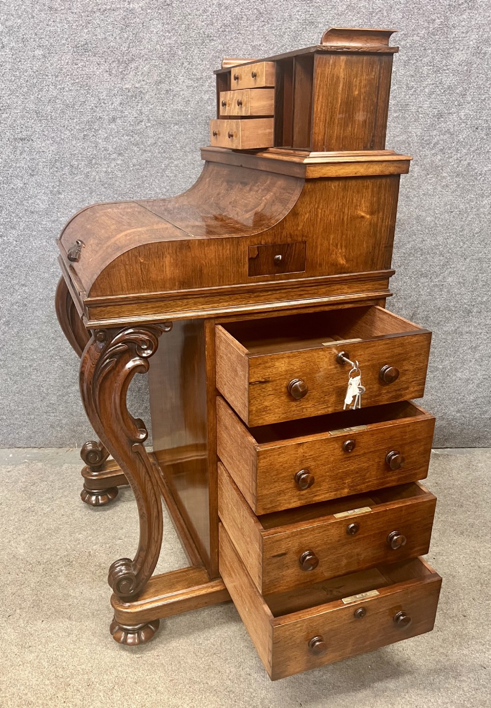 A Victorian rosewood davenport desk with an elevated pop-up stationery gallery, slanted piano top writing slope, side drawers, and carved cabriole support legs. View II