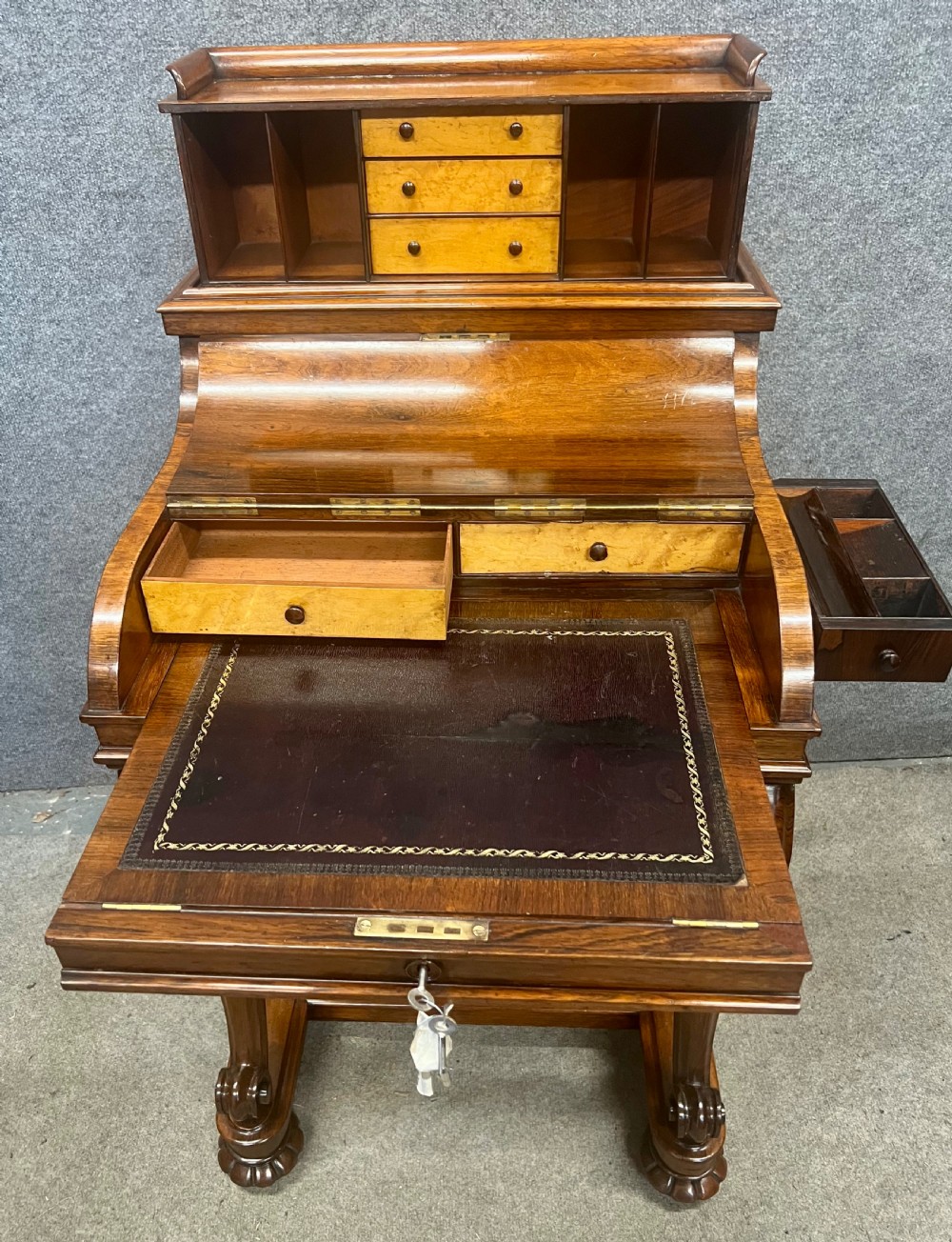A Victorian rosewood davenport desk with an elevated pop-up stationery gallery, slanted piano top writing slope, side drawers, and carved cabriole support legs. View VII