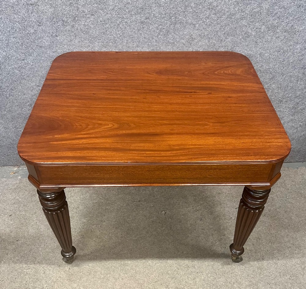 A 19th-century mahogany campaign table featuring turned fluted legs with brass castors and a rectangular polished top. View IV