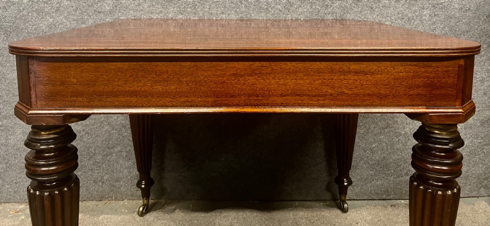 A 19th-century mahogany campaign table featuring turned fluted legs with brass castors and a rectangular polished top. View VI