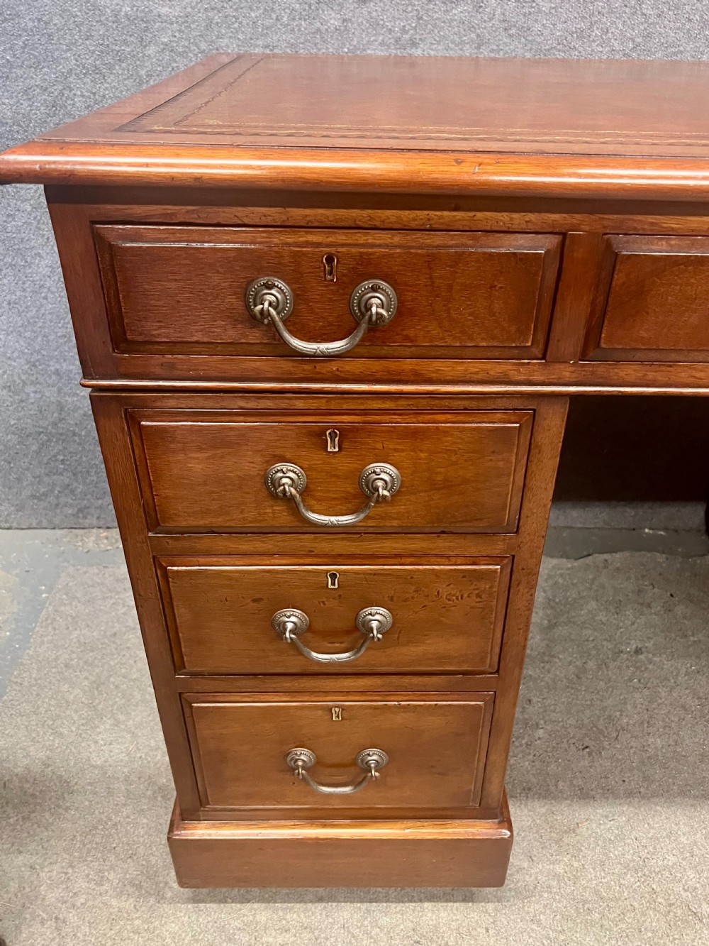 Late Victorian mahogany pedestal desk featuring a brown leather-tooled writing surface, nine drawers with brass handles, and twin pedestals on hidden castors. View III