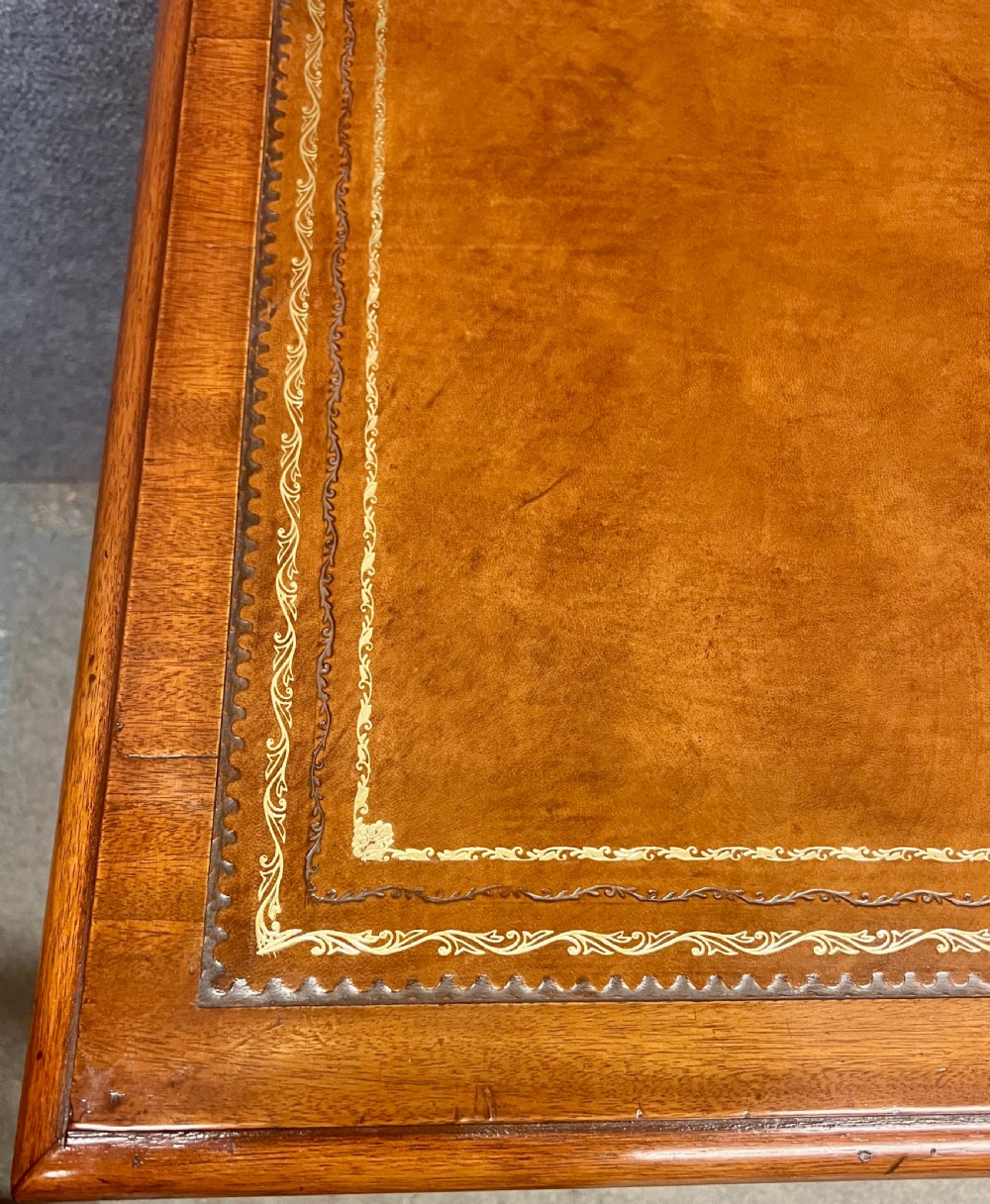 Late Victorian mahogany pedestal desk featuring a brown leather-tooled writing surface, nine drawers with brass handles, and twin pedestals on hidden castors. View V