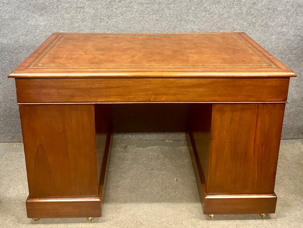 Late Victorian mahogany pedestal desk featuring a brown leather-tooled writing surface, nine drawers with brass handles, and twin pedestals on hidden castors. View VII