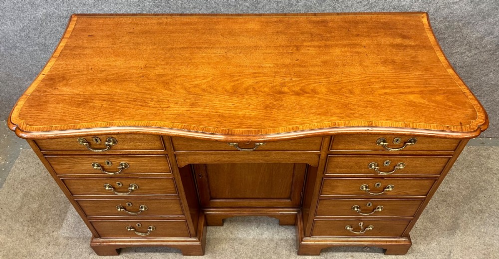 A George III mahogany kneehole desk featuring multiple drawers with brass swan-neck handles, a central recessed cupboard, and bracket feet. View III