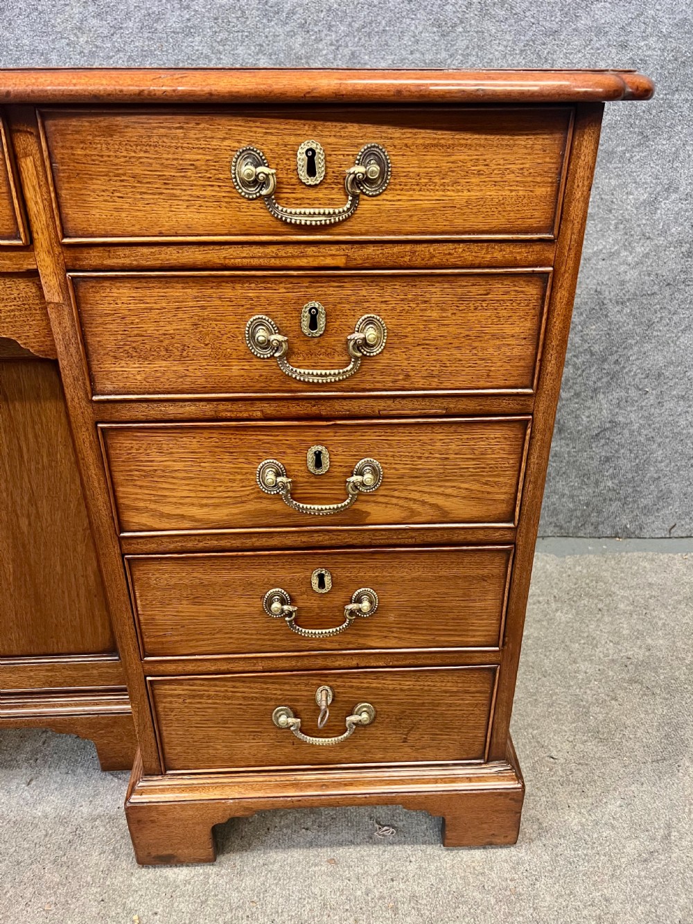 A George III mahogany kneehole desk featuring multiple drawers with brass swan-neck handles, a central recessed cupboard, and bracket feet. View VIII